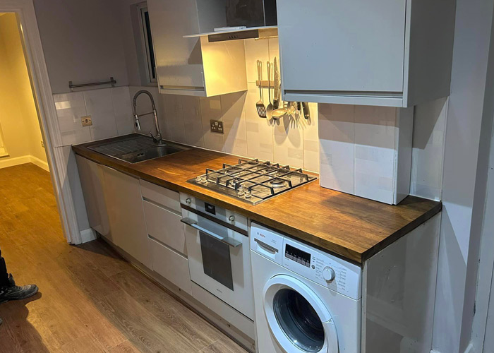 modern kitchen with stainless steel appliances and wooden countertop featuring a gas stove and washing machine ideal for home cooks and laundry in one space 3 functional areas